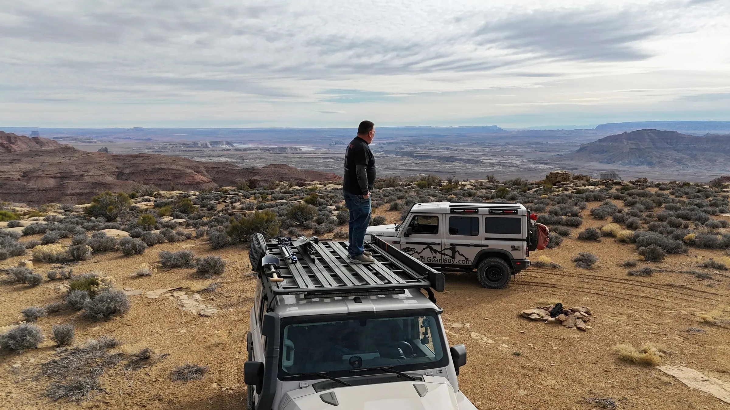 Driver standing on a roof rack at a scenic desert overlook