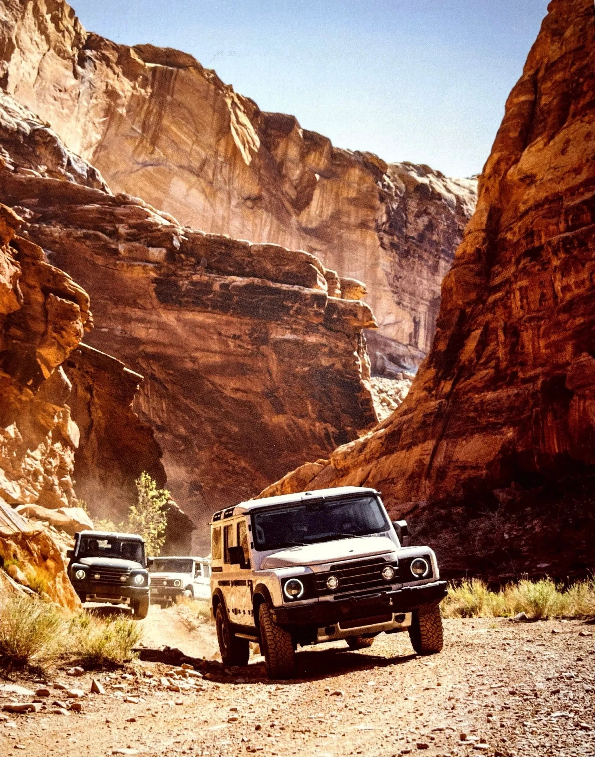 Two 4x4s driving through a narrow red sandstone canyon